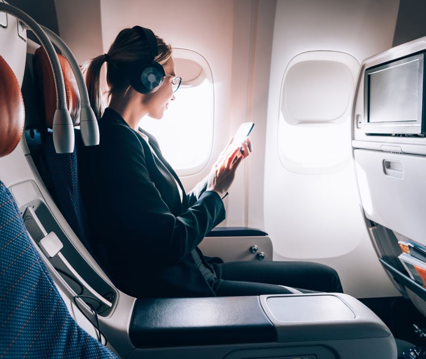 A woman using her phone learning how to speed up Wi-Fi in an airplane.