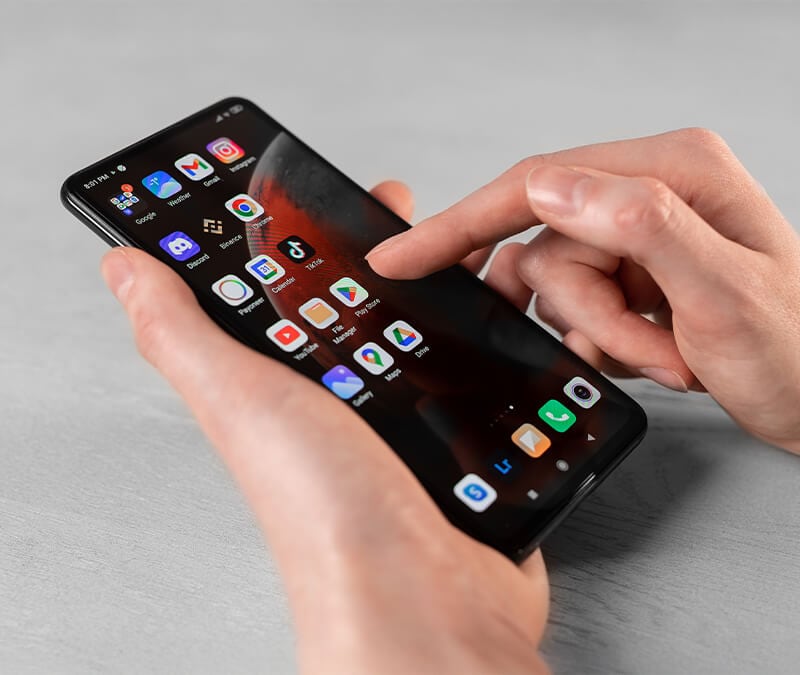 Someone holding a phone, trying to stop their Android apps crashing.