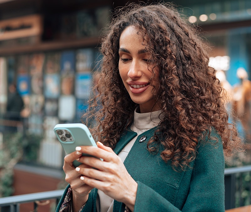 A photograph of a confident woman checking her iPhone for viruses.