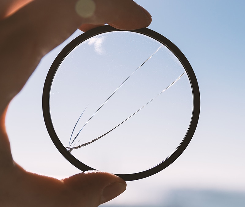A hand holds a cracked looking glass, which represents a cracked VPN tunnel.
