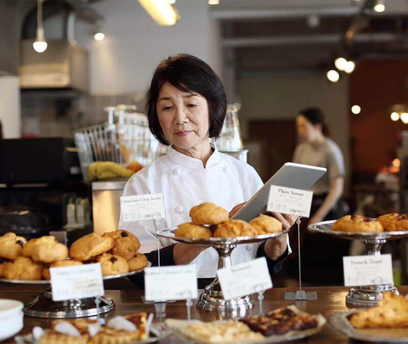 The owner of a small local bakery inventories baked goods on display.