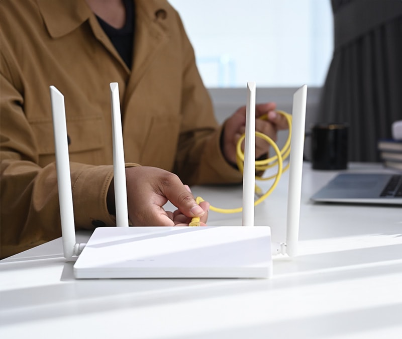 A person unplugging their Wi-Fi router to reset their IP address.
