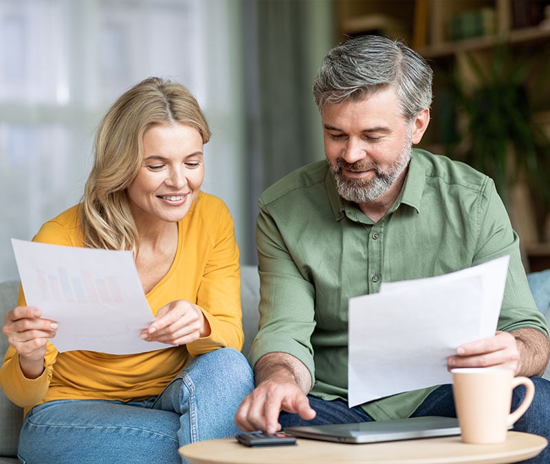 A middle-aged couple examining their financial statements as part of their early retirement planning.