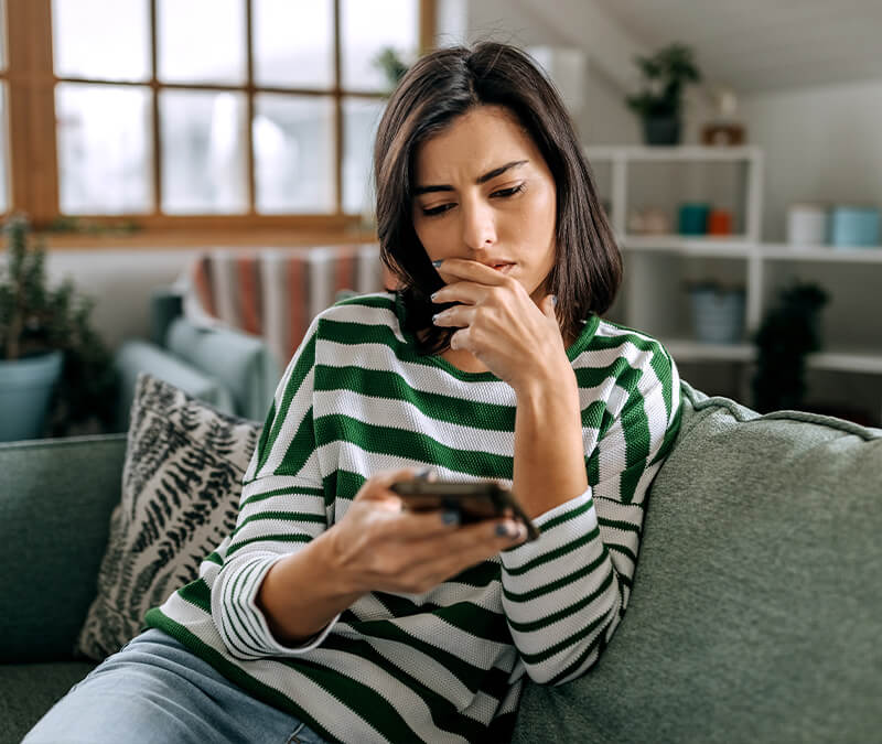 A woman looking at spam texts on her phone.