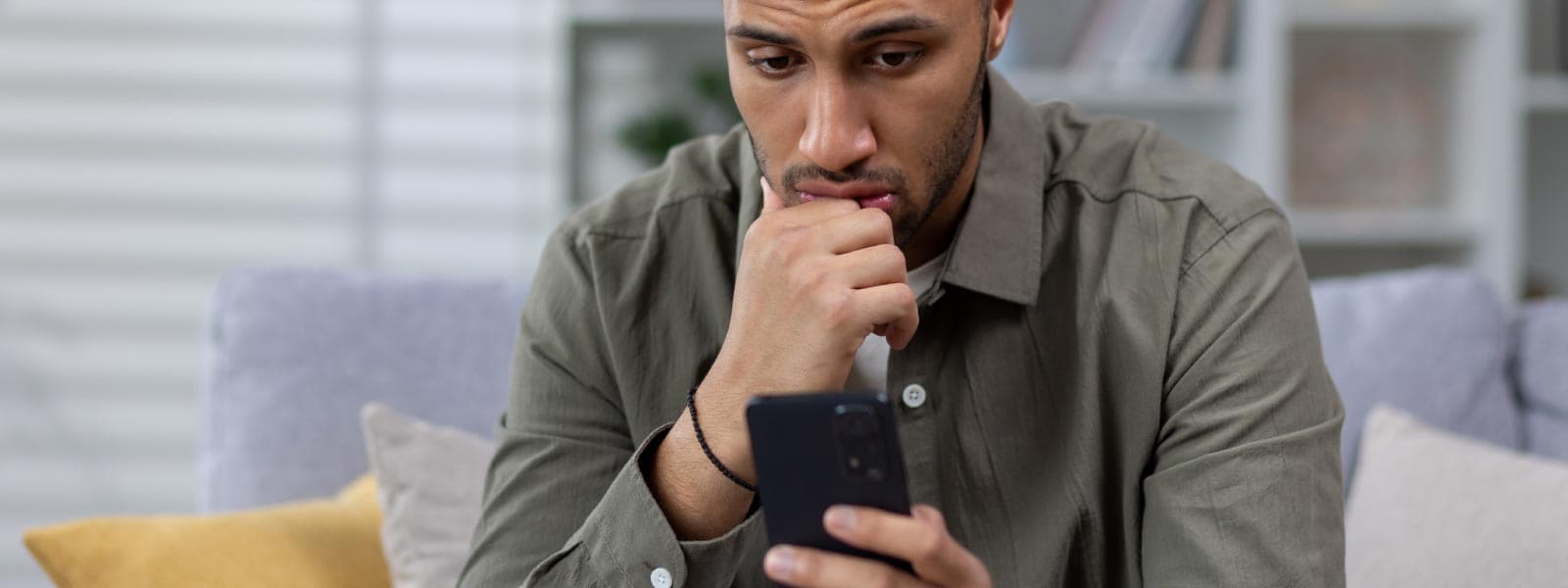 Worried man looking at his phone unsure if it is tapped or tracked.