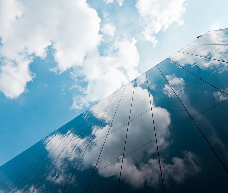 Clouds float by in the sky and are reflected in a building’s windows.