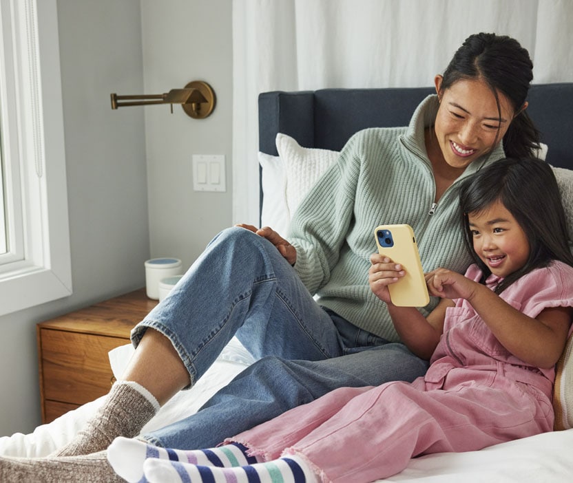 A mother and daughter browsing a device that is protected from malware like computer worms.