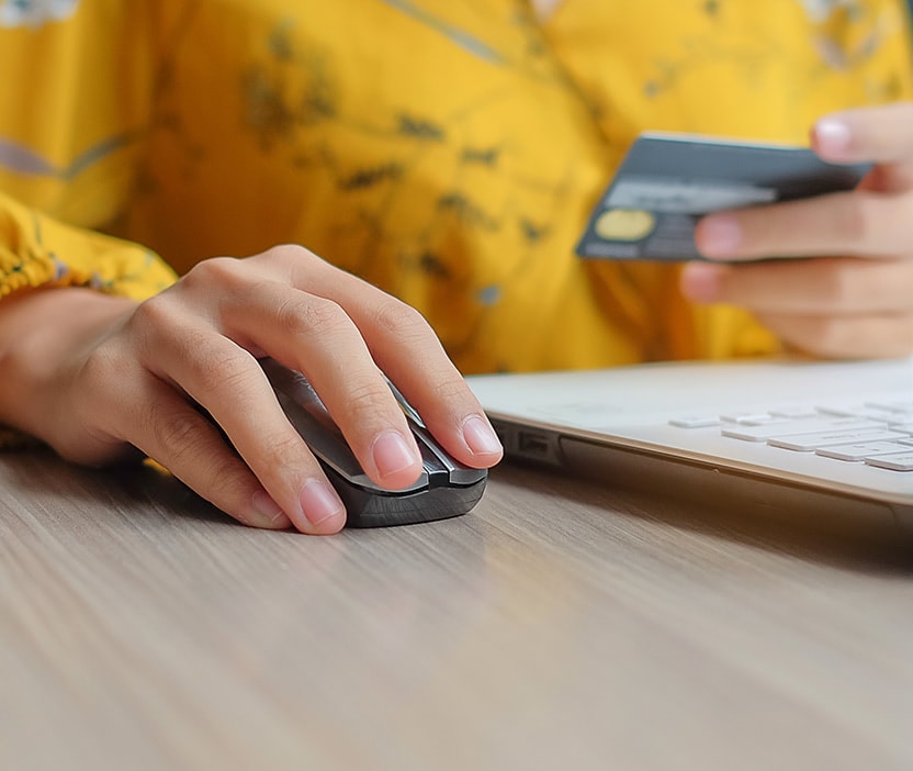 A person using a computer, with their fingers hovering over the mouse and a credit card in the background, illustrating the importance of balancing privacy and security.