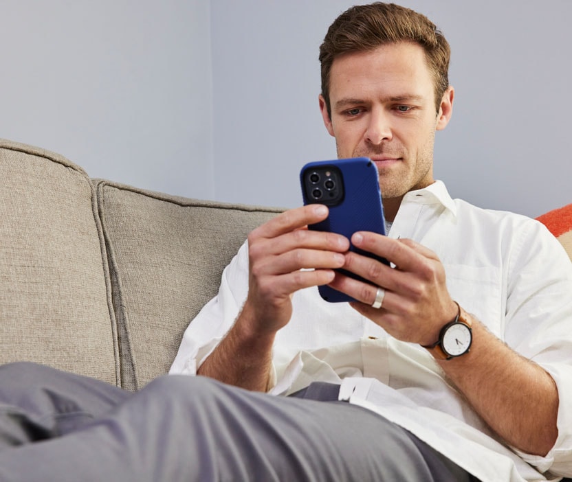 A man holding a blue phone, looking for a solution to unlock his blocked Facebook account.