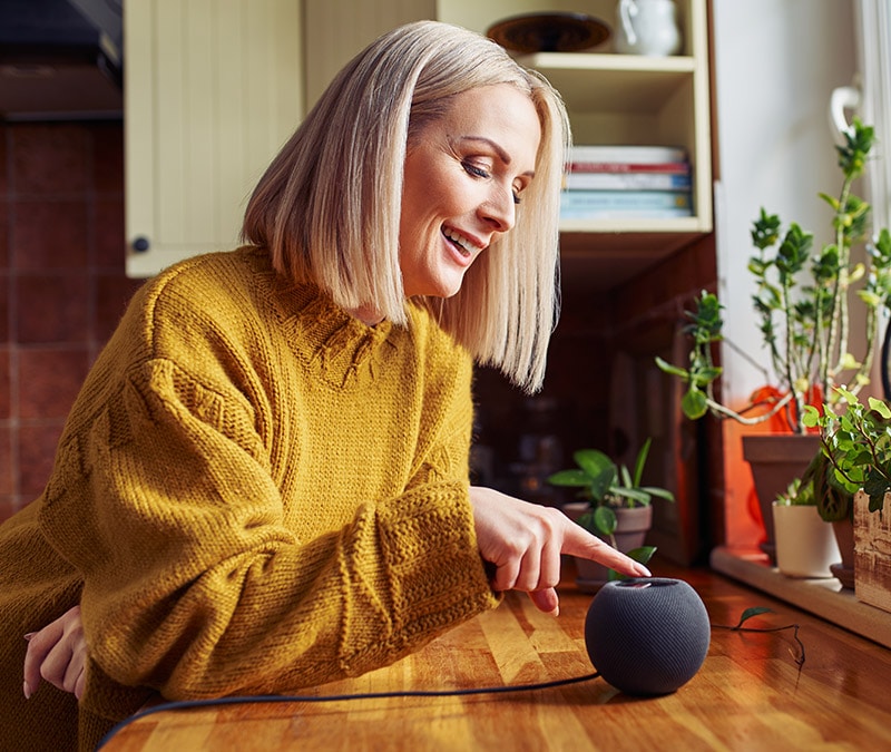 A woman happily holding a Google Home Mini, a smart speaker.