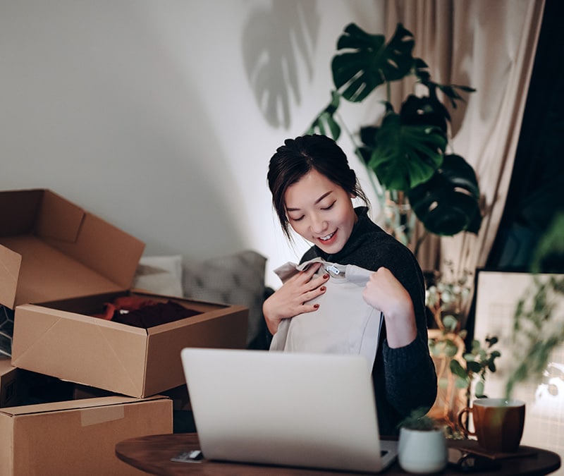 A woman holding a top from a newly opened package and wondering if AliExpress is legit.