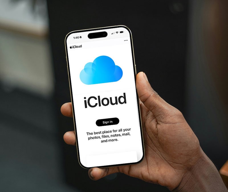 A person holding an iPhone with iCloud displayed on the screen.