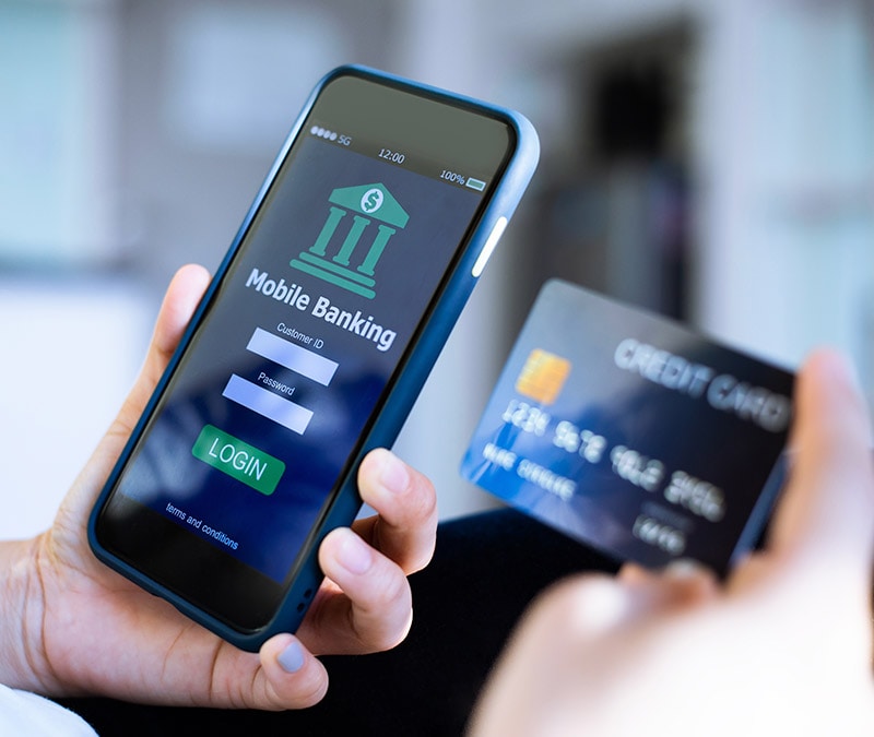 Someone looking at a mobile banking app on their phone and a credit card.