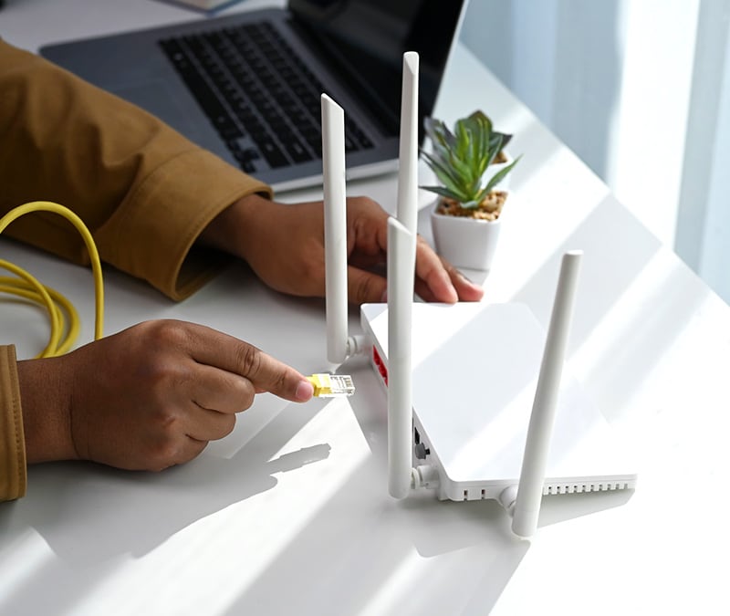 Someone plugging in a router to the internet, working through how to secure their Wi-Fi.