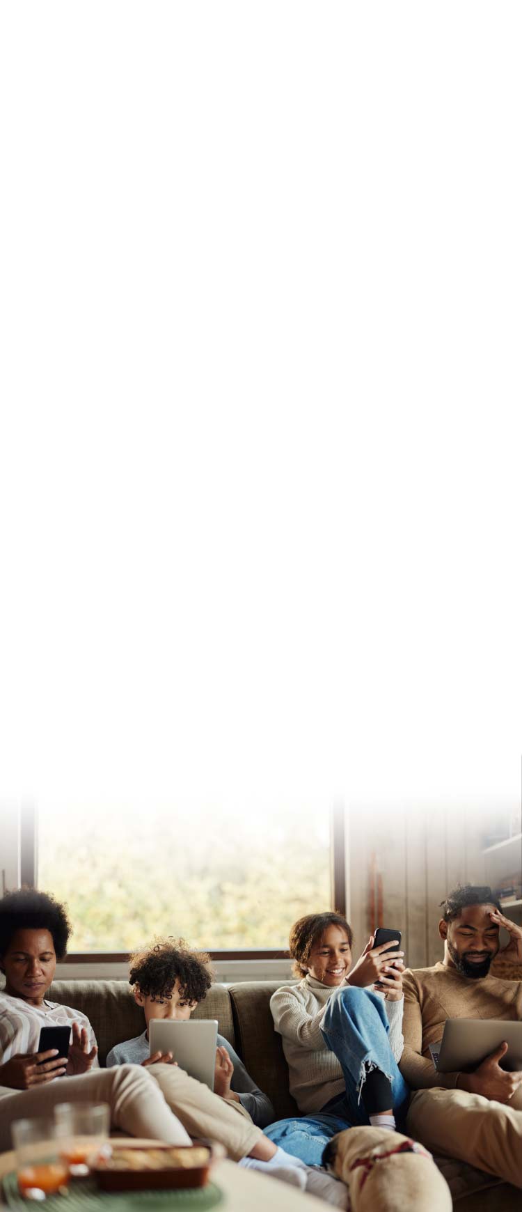 A family lounges on their couch, each using a different device.