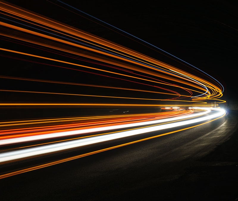 Streaks of light in a tunnel, symbolizing high speed connections following Norton VPN performance upgrades.