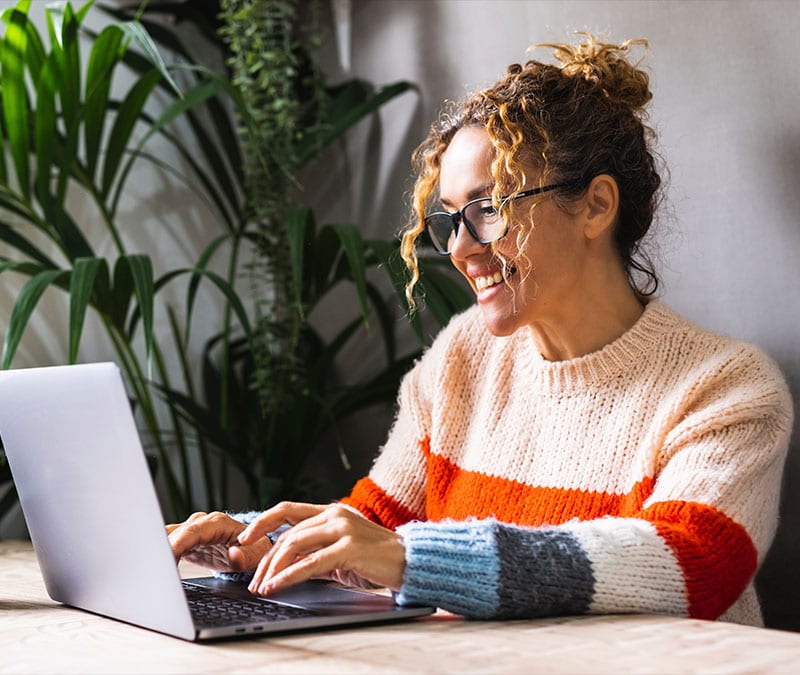 A woman browsing confidently on her laptop, enjoying the new Norton Private Browser privacy, security, and utility features.