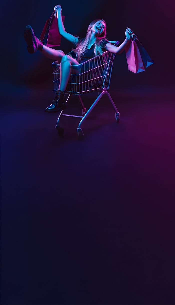 A woman happily riding in a shopping cart, symbolizing online shopping scam safety.