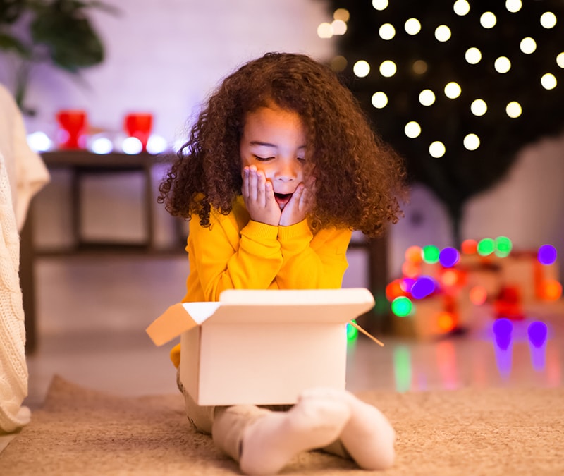 Little girl with yellow surprised at the smart toy she was gifted