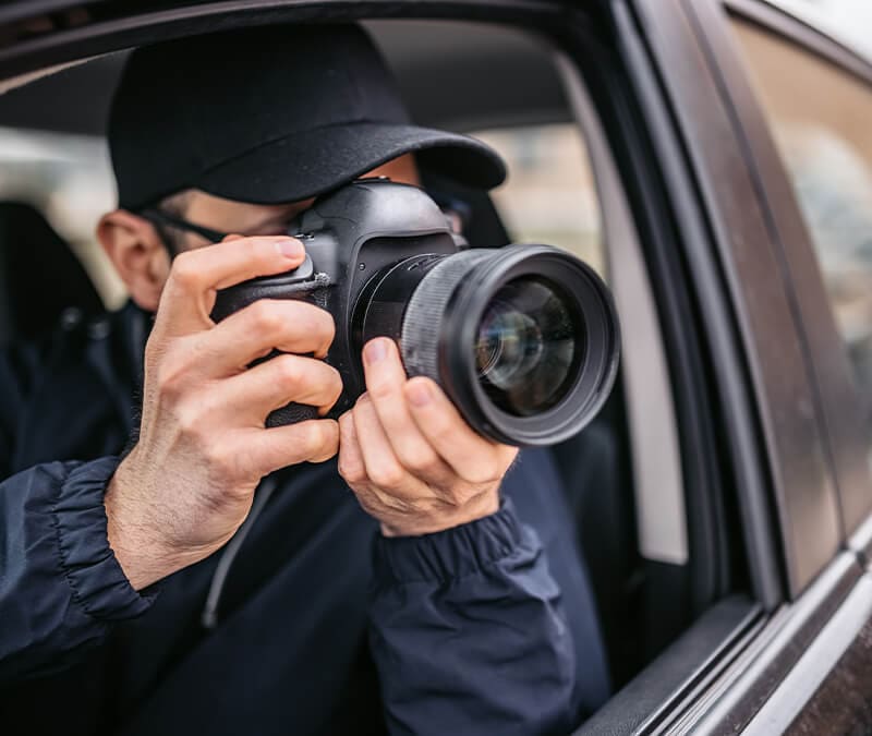 A man with a camera in a car spying on his neighbors.