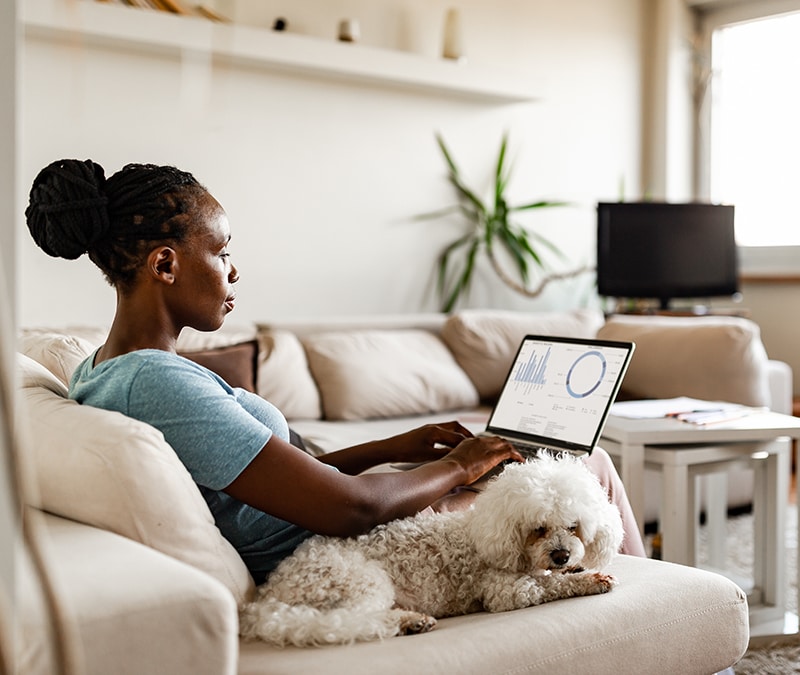 A woman looking at the computer next to her dog.