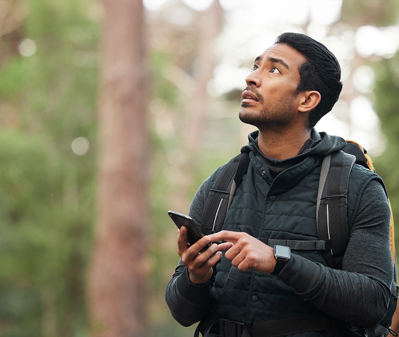 A man in the woods trying to check his location on his iPhone.