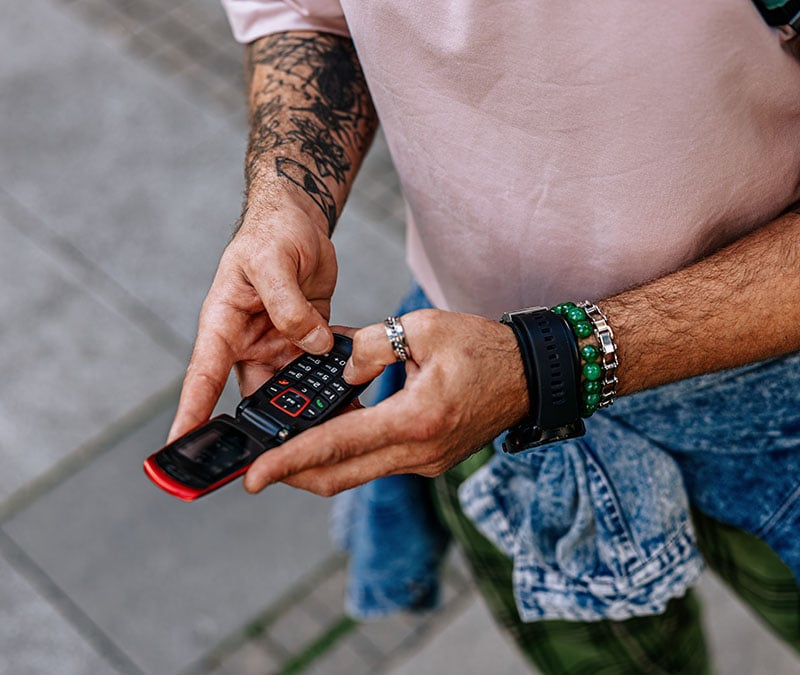 A man using a flip-top burner phone.