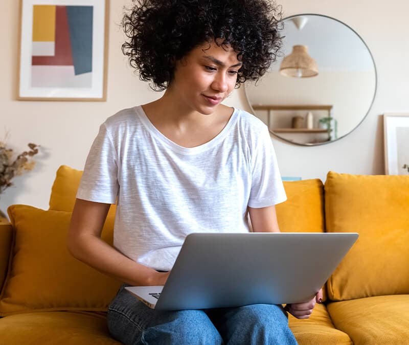 A woman with a white shirt and curly hair checks a site’s SSL certificate on her laptop.