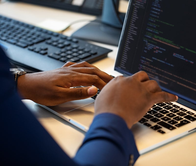 A set of hands sit on top of a laptop.