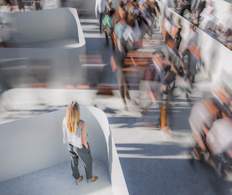 A woman stands on a platform and watches people speed by.