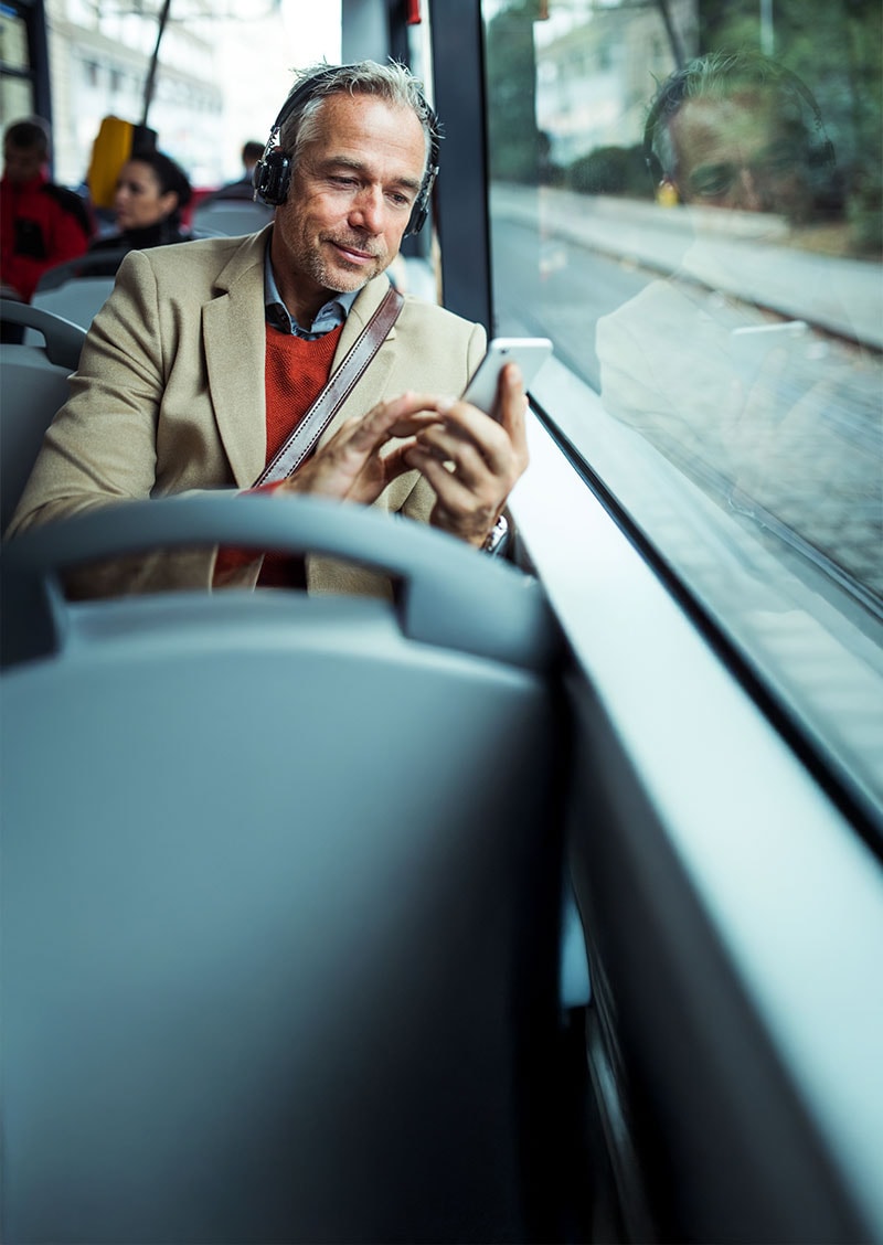 A man riding the bus and enjoying fast and smooth phone performance.