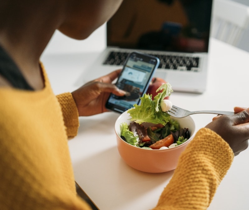 A woman eating a salad goes to answer her phone and realizes it's a fake number.