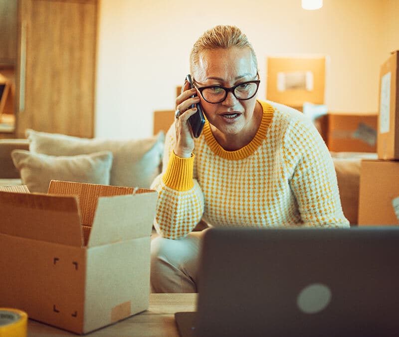 A picture of someone on the phone with an open package, concerned she was the victim of a brushing scam.