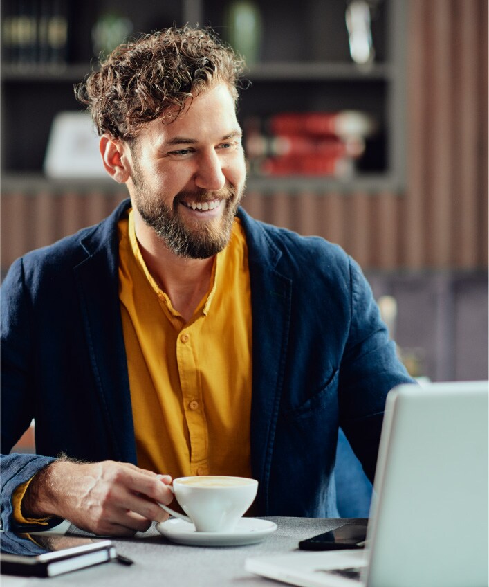 A man wearing a yellow shirt looking at his digital footprint on his computer screen.