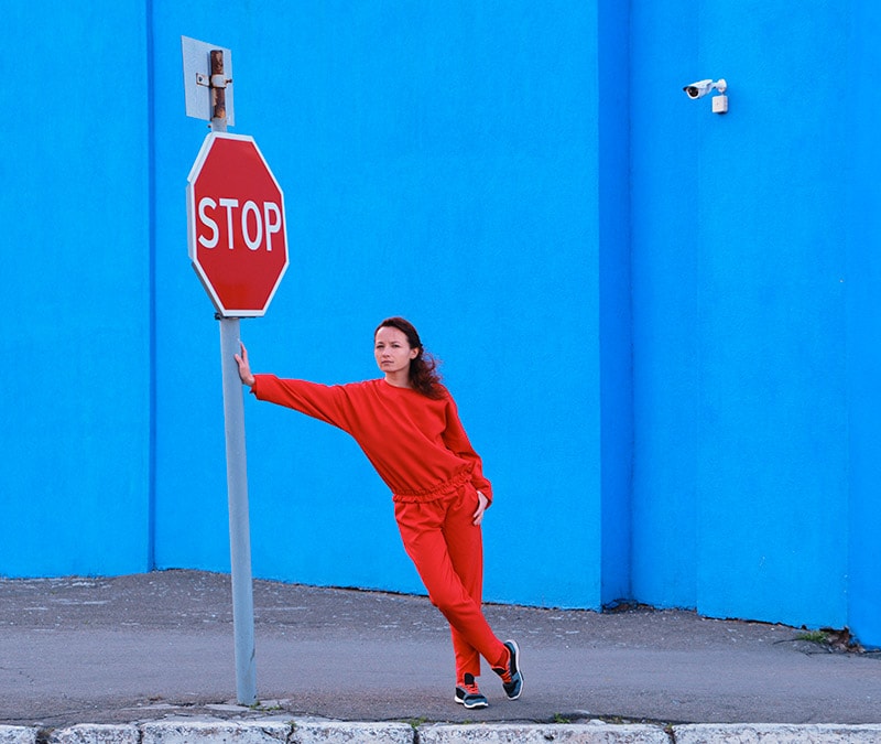 An image of a woman leaning against a stop sign