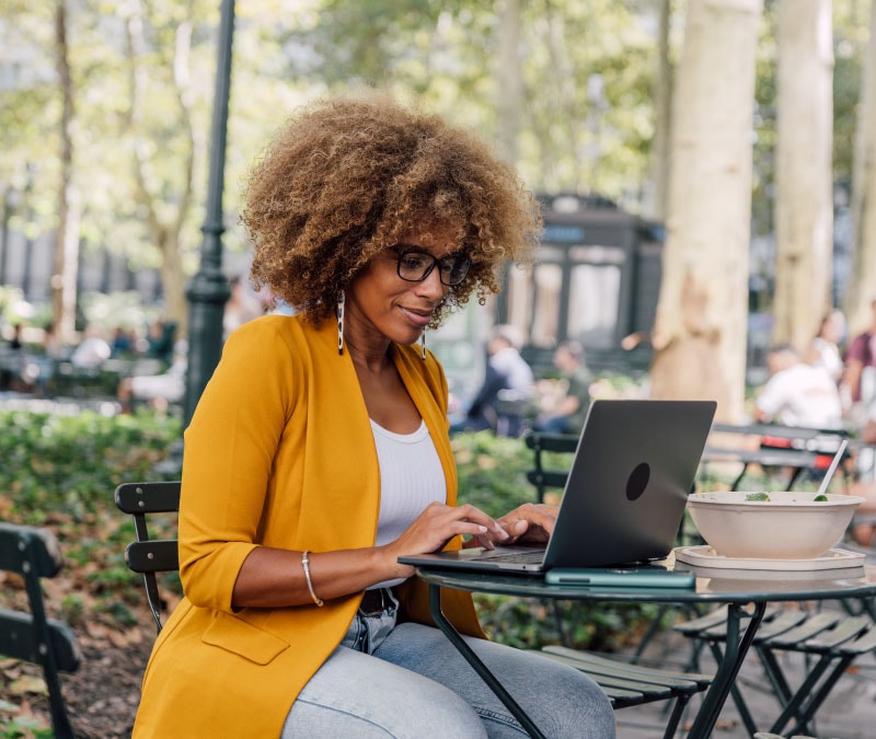 A woman uses a VPN to keep company data private while working from a patio.