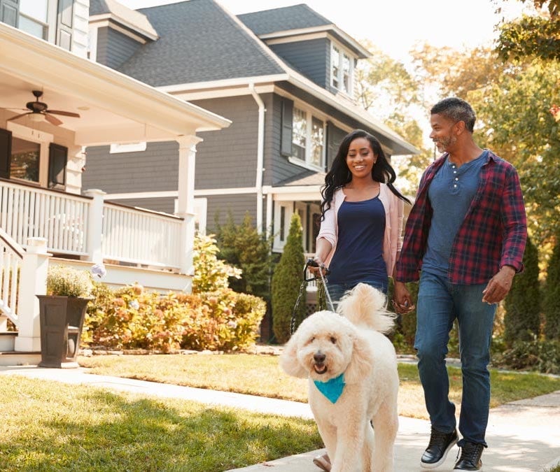 A family with a white dog walks outside their second home, which they bought with a home equity loan.