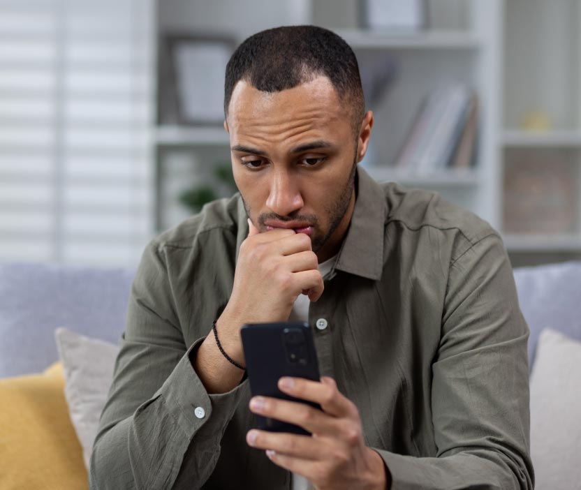 Worried man looking at his phone unsure if it is tapped or tracked.