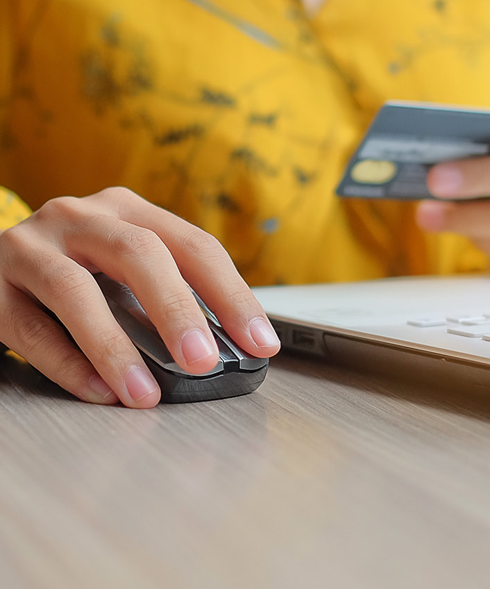 A person using a computer, with their fingers hovering over the mouse and a credit card in the background, illustrating the importance of balancing privacy and security.