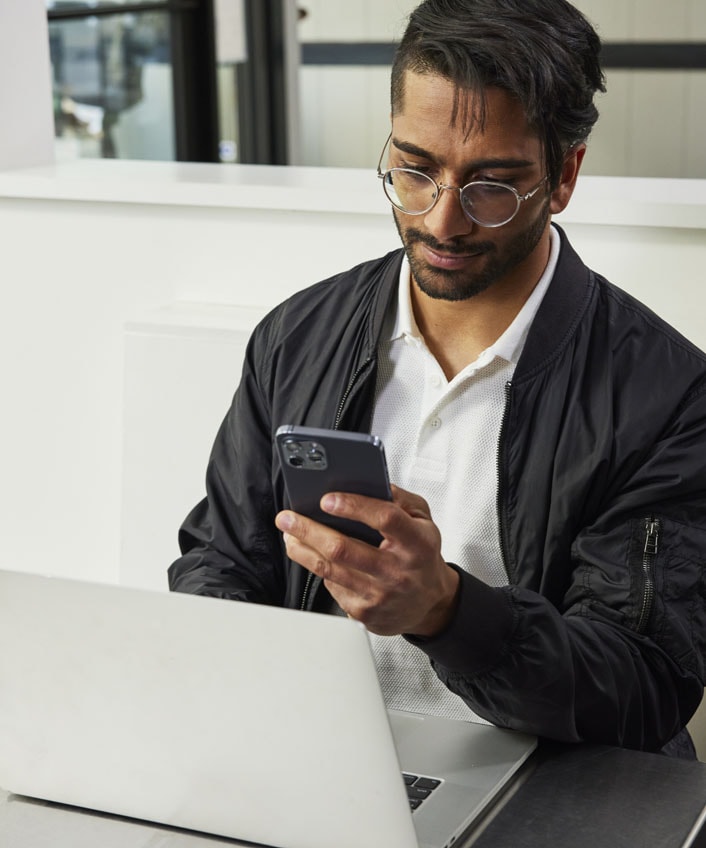 A man wearing glasses and a jacket, looking concerned about online scams.