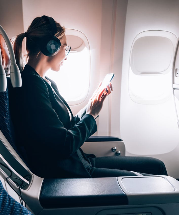 A woman using public Wi-Fi on a flight, taking precautions to stay safe online.