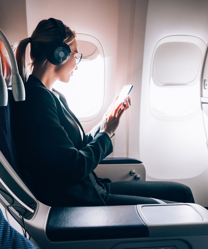 A woman using her phone learning how to speed up Wi-Fi in an airplane.