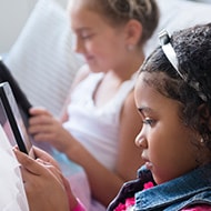 Children playing on mobile devices with parental controls enabled.