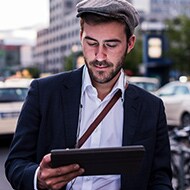 A man securely entering a password into a laptop while walking outside, illustrating the security of password managers.