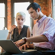 A man and woman working together on a laptop, discussing the potential of the Internet of Things.