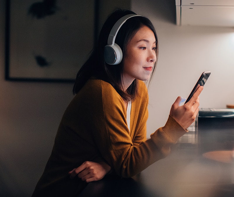 Person is looking at social media tips on her smartphone in a cozy, softly lit environment.