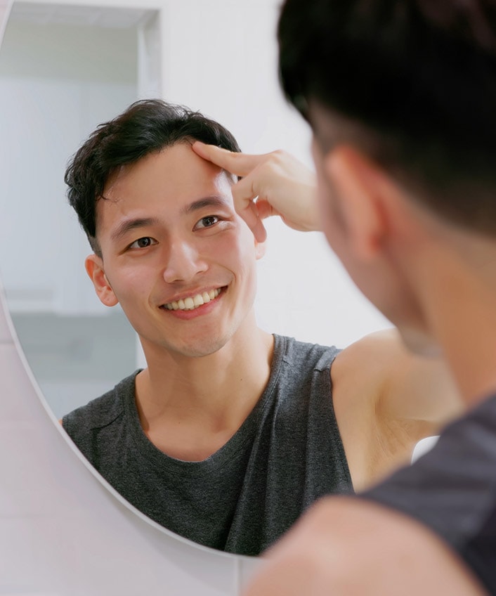 A man looking in the mirror as an example of social engineering, a malicious tactic used to gain access to confidential information.