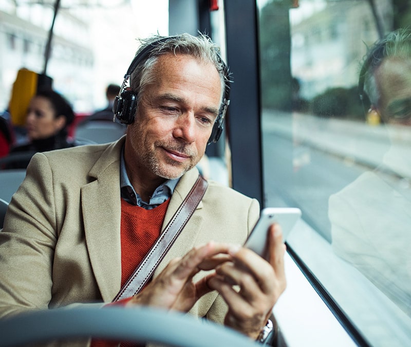 A man riding the bus and enjoying fast and smooth phone performance.