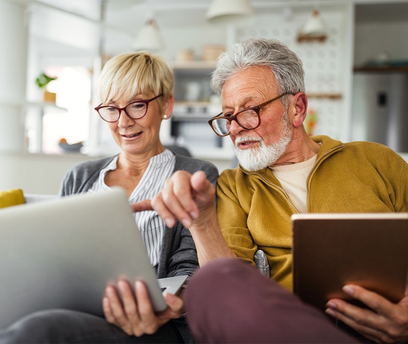 A couple sitting on a couch, looking at a laptop, and trying to figure out how to withdraw money from a 401(k).