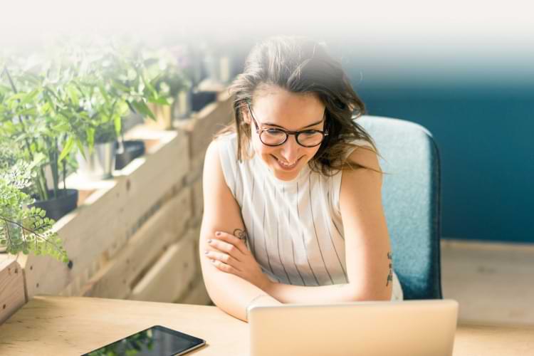 Smiling woman sitting at a desk looking at her laptop